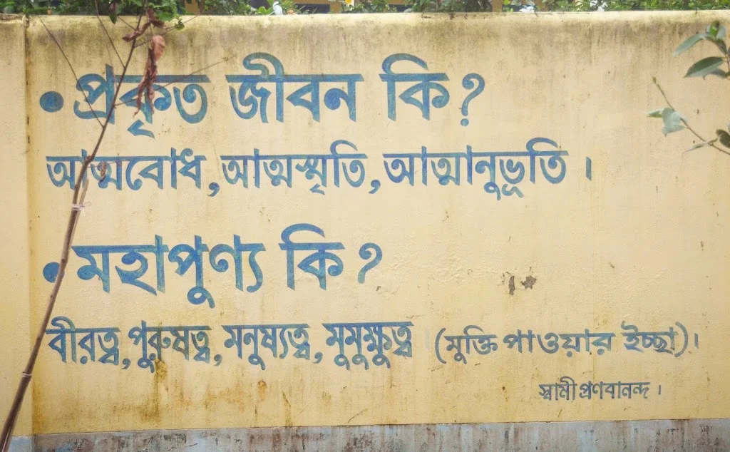 Bangla quotes by Swami Pranavananda on real life and virtue at Naogaon Sevashram Sangha wall.
