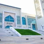 Front view of Naogaon Sadar Upazila Model Mosque with white-themed modern design and marble stairs, 2023.