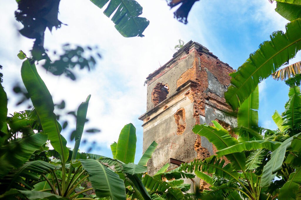 Ruins of a palace seen through loopholes framed by banana leaves, photo taken in 2023 AD.