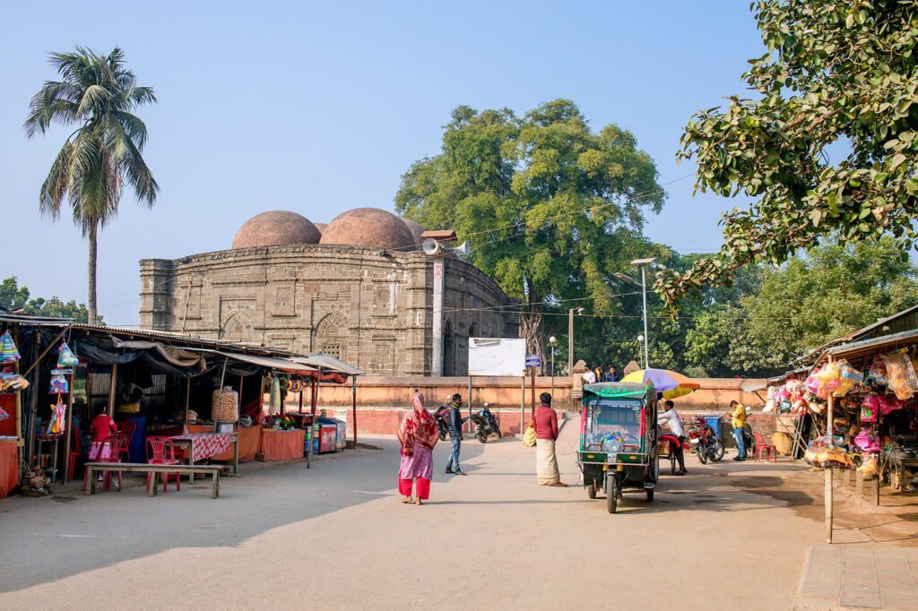 Kusumba Mosque viewed from the south side with the adjacent bazaar on a sunny day.