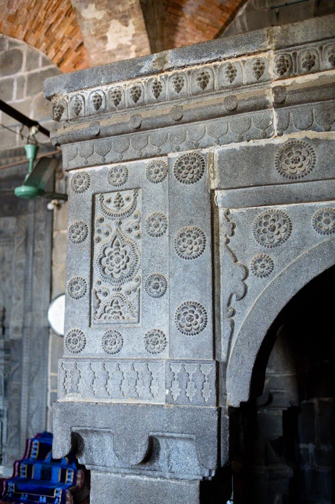 Stone curved floral artwork on the corner pillar of the north wall's Mihrab.