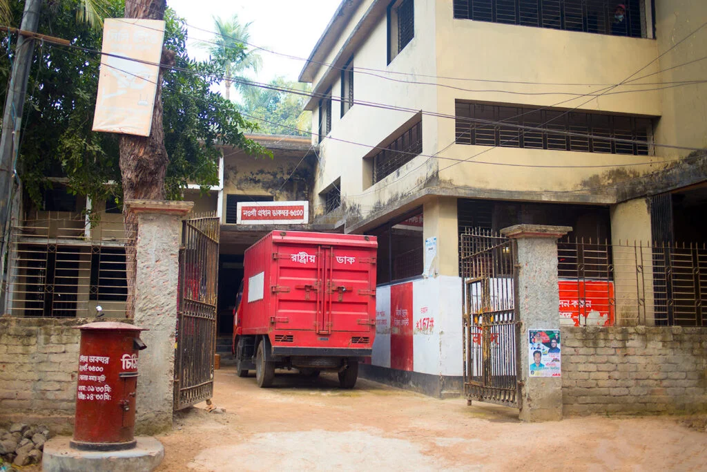 Naogaon district post office building on Post Office Rd, postal code 6500, in front of Pourasabha gate.